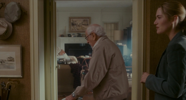 Wide shot frame from The Holiday — standing, room, suit