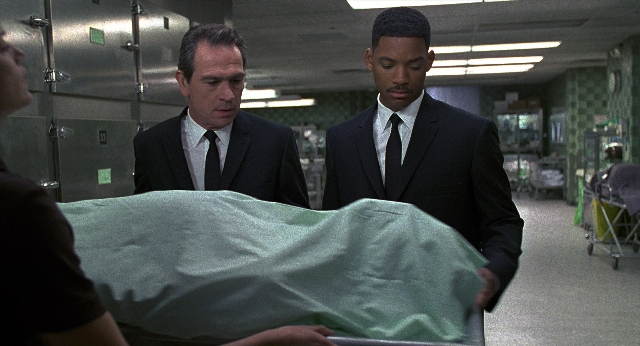 Wide shot frame from Men in Black — standing, suit, tie