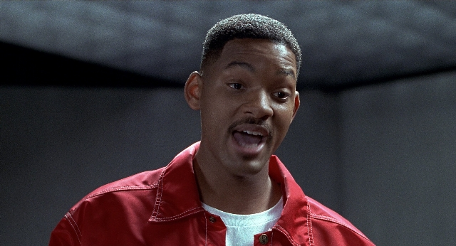 Medium shot frame from Men in Black — shirt, jacket, mustache