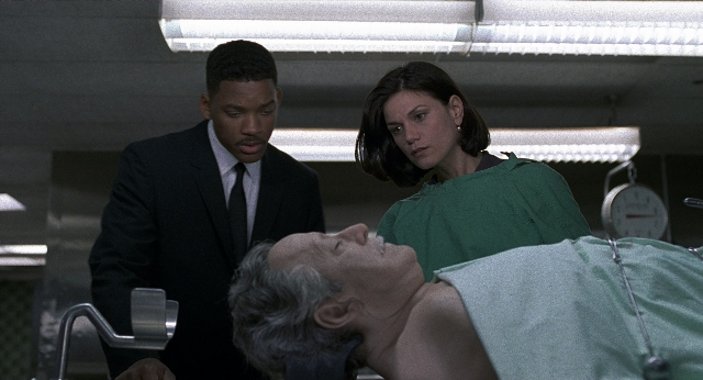 Wide shot frame from Men in Black — standing, bed, suit