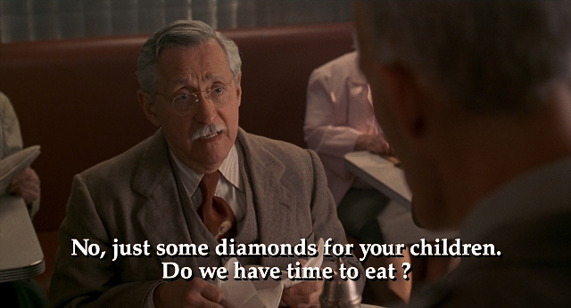 Wide shot frame from Men in Black — sitting, table, suit