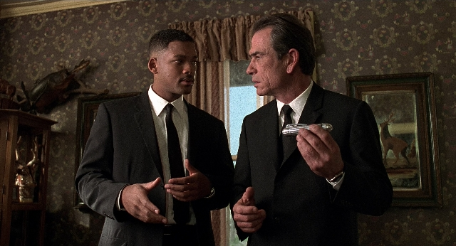 Wide shot frame from Men in Black — room, dialogue, hand