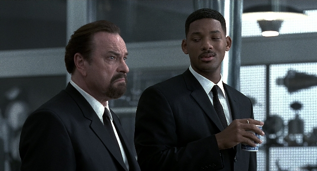 Wide shot frame from Men in Black — standing, hand, suit