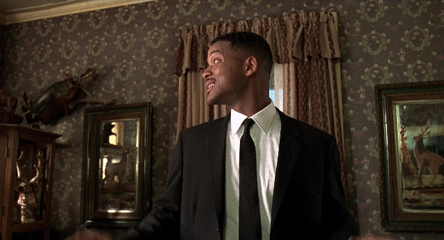 Wide shot frame from Men in Black — standing, room, suit