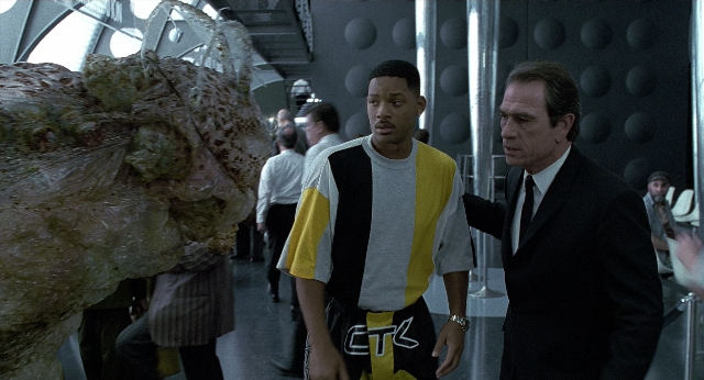 Wide shot frame from Men in Black — standing, suit, tie