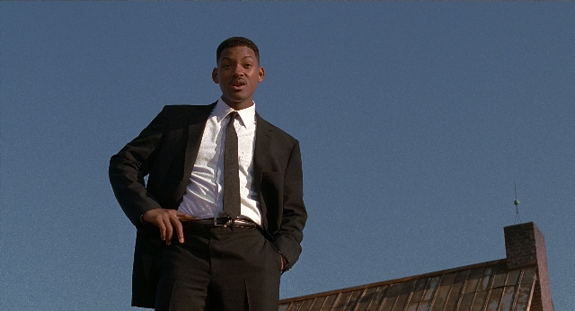 Wide shot frame from Men in Black — standing, suit, tie