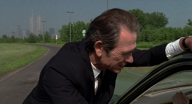 Wide shot frame from Men in Black — street, car, suit