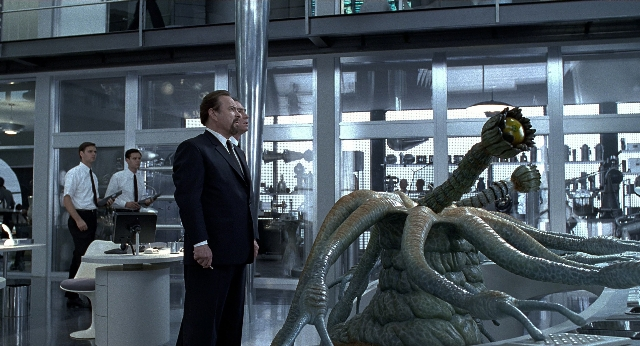 Wide shot frame from Men in Black — standing, suit, tie