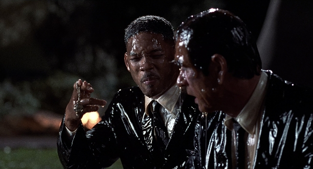 Wide shot frame from Men in Black — standing, room, dialogue