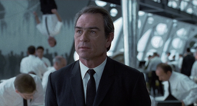 Medium shot frame from Men in Black — standing, room, suit