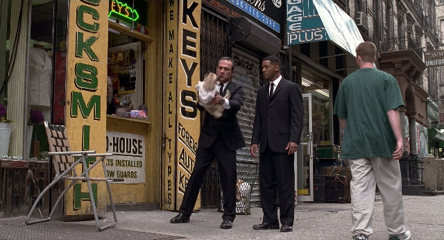 Wide shot frame from Men in Black — walking, street, dog