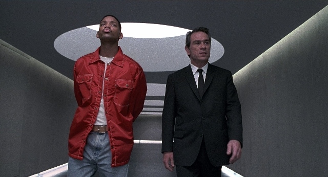 Wide shot frame from Men in Black — standing, room, suit
