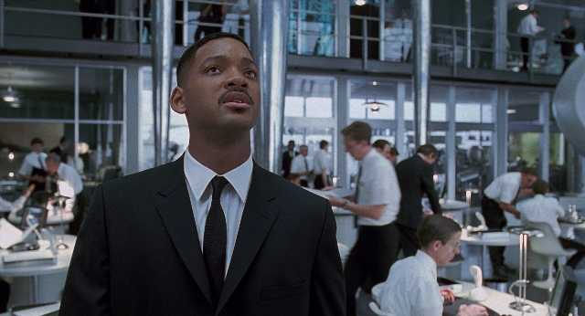 Wide shot frame from Men in Black — standing, suit, tie