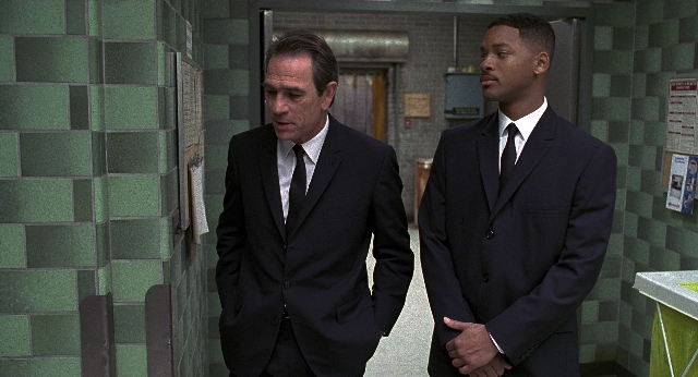 Wide shot frame from Men in Black — walking, dialogue, door