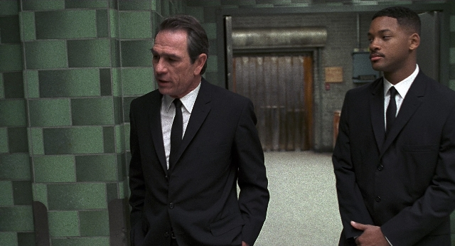 Wide shot frame from Men in Black — walking, dialogue, door