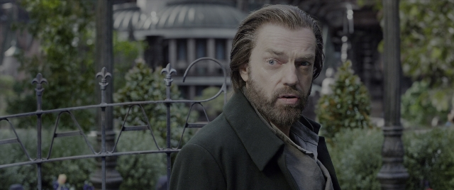Medium shot frame from Mortal Engines — standing, coat, beard