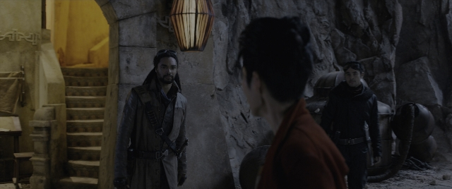Wide shot frame from Mortal Engines — standing, dialogue, coat