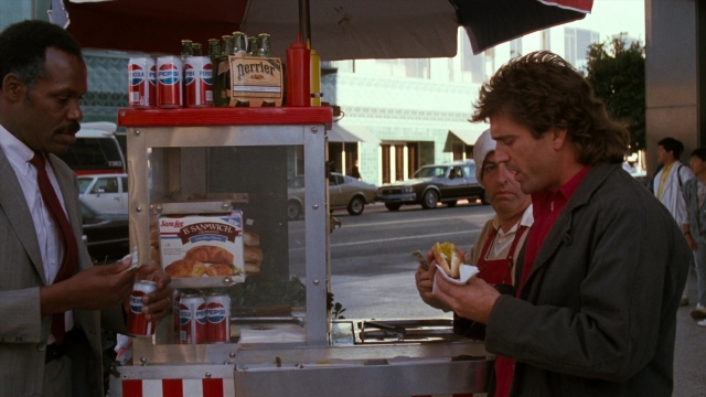 Wide shot frame from Lethal Weapon — standing, dialogue, street