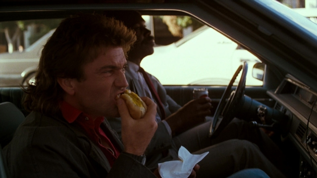 Wide shot frame from Lethal Weapon — sitting, street, dog