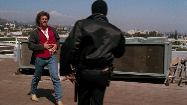 Wide shot frame from Lethal Weapon — standing, dialogue, hand