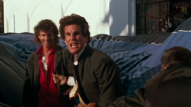 Wide shot frame from Lethal Weapon — standing, dialogue, hand