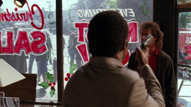 Wide shot frame from Lethal Weapon — standing, table, street