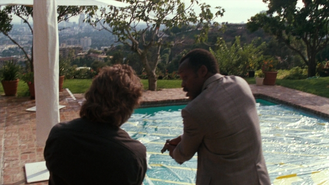Wide shot frame from Lethal Weapon — sitting, standing, suit