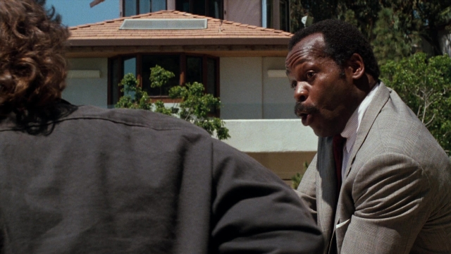 Wide shot frame from Lethal Weapon — sitting, suit, tie