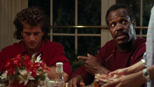Medium shot frame from Lethal Weapon — sitting, room, table