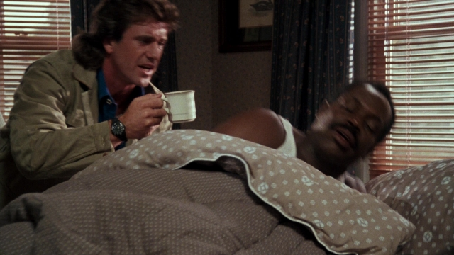 Wide shot frame from Lethal Weapon — sitting, bed, bedroom