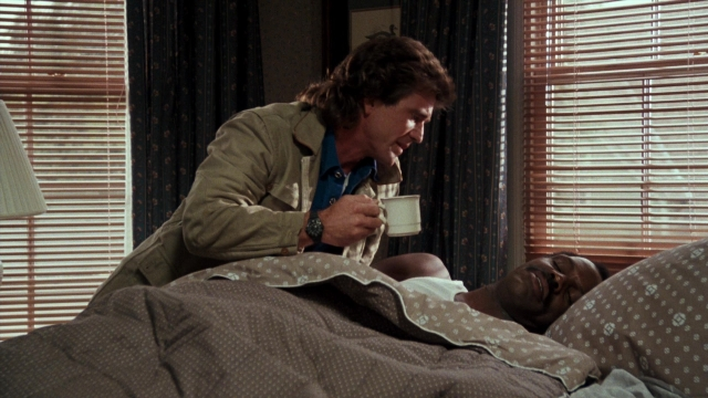 Wide shot frame from Lethal Weapon — standing, room, bed