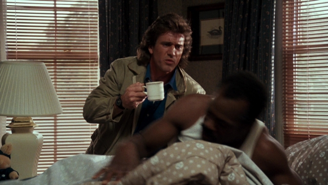 Wide shot frame from Lethal Weapon — standing, room, bed