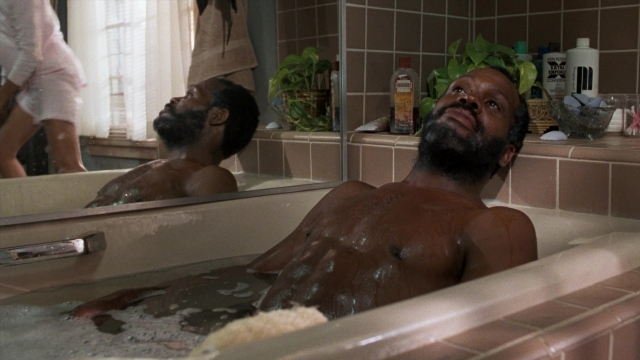 Wide shot frame from Lethal Weapon — sitting, standing, mirror