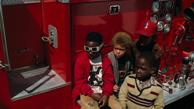Wide shot frame from Lethal Weapon — sitting, door, hat