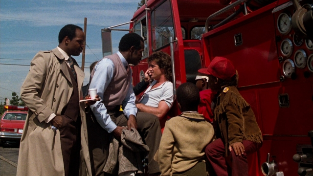Wide shot frame from Lethal Weapon — sitting, standing, dialogue