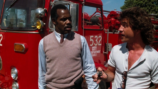 Wide shot frame from Lethal Weapon — standing, dialogue, fire