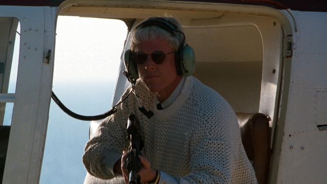 Wide shot frame from Lethal Weapon — sitting, hand, gun