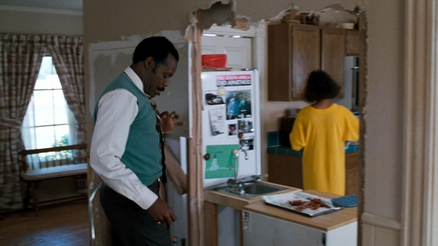 Wide shot frame from Lethal Weapon — standing, refrigerator, house
