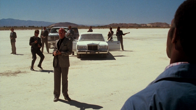 Medium shot frame from Lethal Weapon — standing, dialogue, car