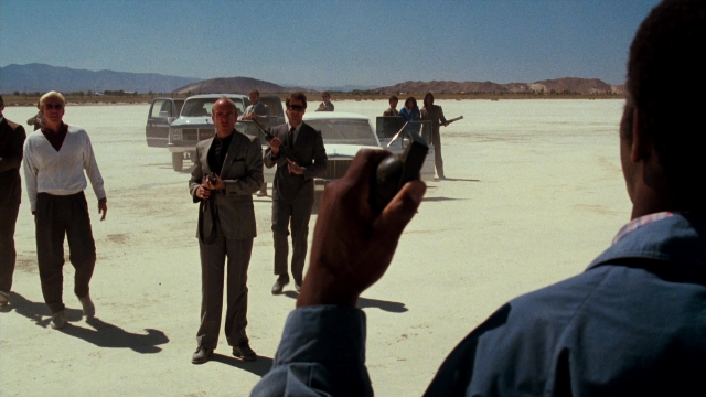 Wide shot frame from Lethal Weapon — standing, dialogue, suit