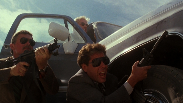 Wide shot frame from Lethal Weapon — street, car, gun