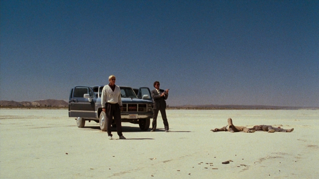 Wide shot frame from Lethal Weapon — standing, hat, car