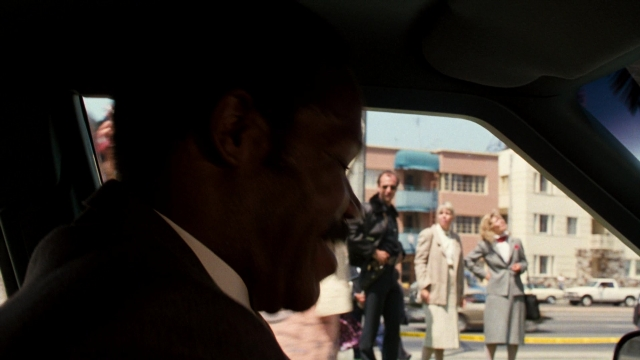 Wide shot frame from Lethal Weapon — sitting, walking, street