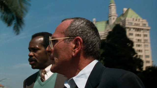 Wide shot frame from Lethal Weapon — standing, dialogue, suit