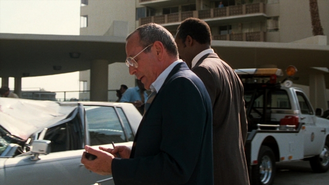 Wide shot frame from Lethal Weapon — standing, phone, car