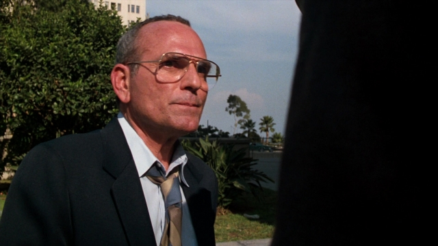 Medium shot frame from Lethal Weapon — standing, suit, tie
