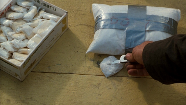 Wide shot frame from Lethal Weapon — hand, bag, box