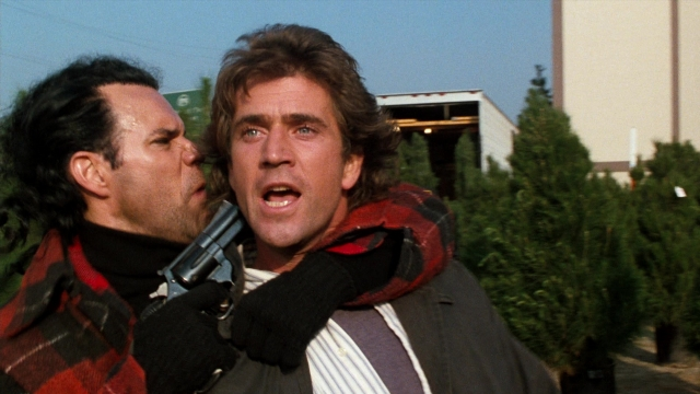 Medium shot frame from Lethal Weapon — standing, suit, tie