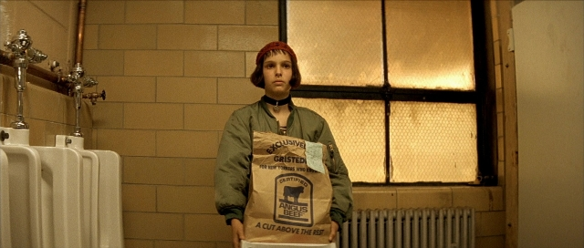 Wide shot frame from Léon — standing, face, bag