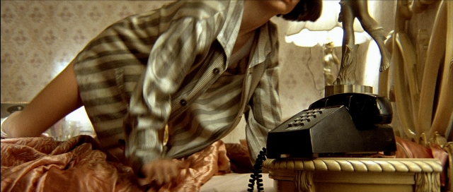 Wide shot frame from Léon — bed, phone, shirt